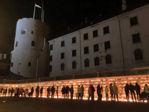 Cilvēki noliek sveces pie Rīgas mūra 11.Novembrī